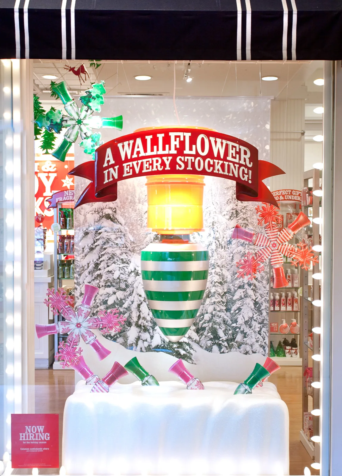 Holiday window, a six-foot ornament under a banner reading A wallflower in every stocking