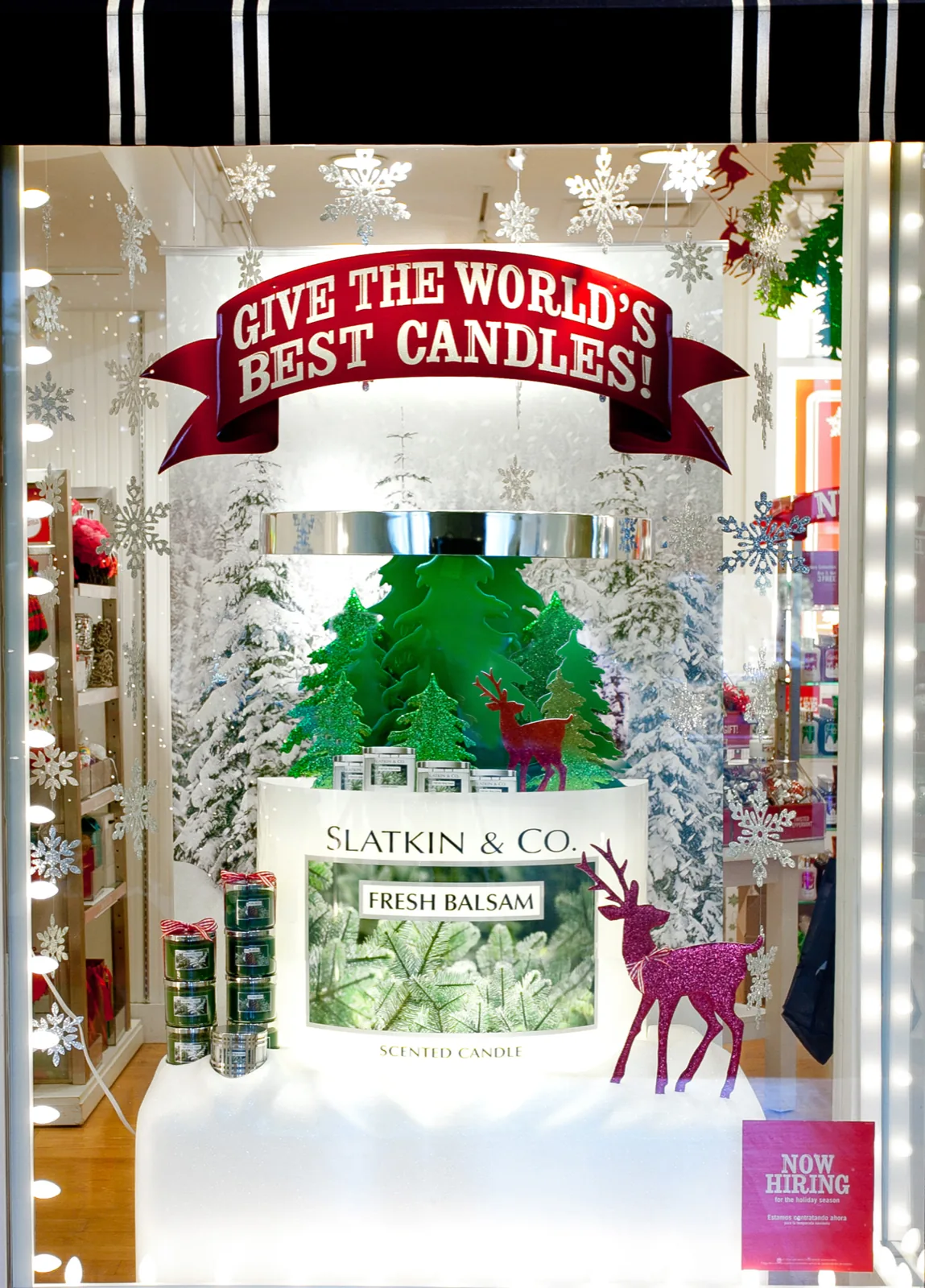 Holiday window, glitter firs and a magenta reindeer under Give the world’s best candles