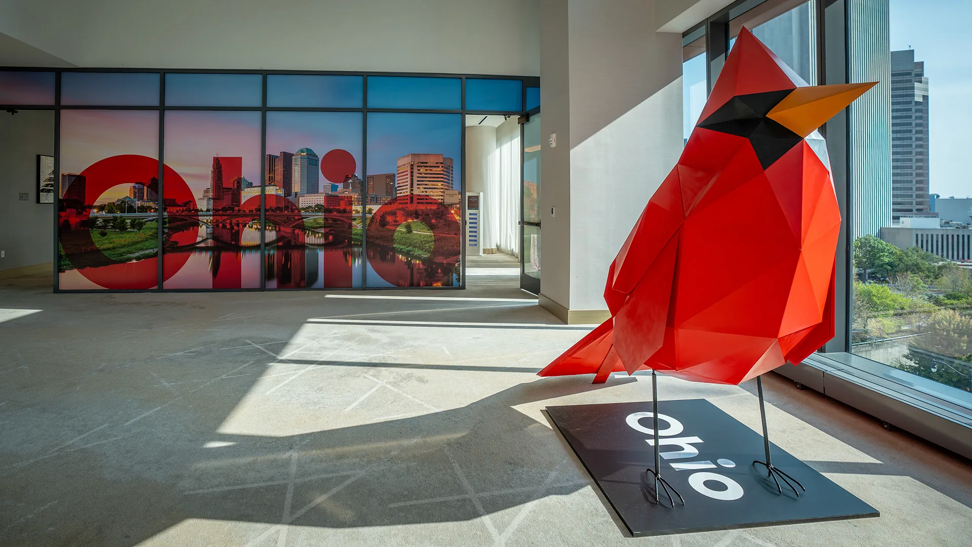 The cardinal in the room it was built for, window film carrying the skyline behind it